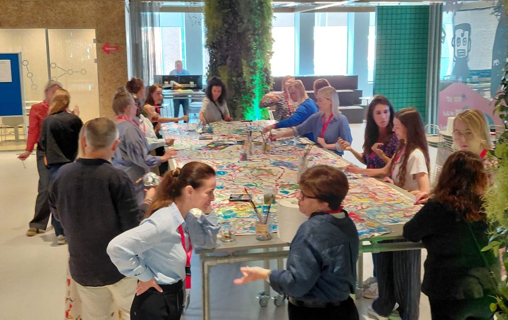 People around a large table painting and talking to each other.