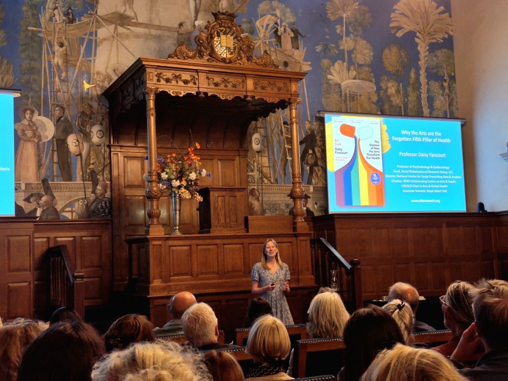 A person speaking in front of an audience in a lecture hall.