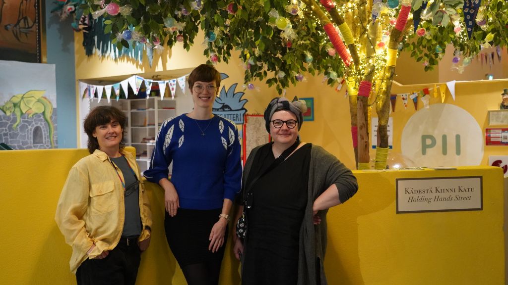 Anna Lord, Rachel Rothwell ja Piia Kleimola seisovat yhdessä hymyillen Kulttuurikeskus PiiPoon tiloissa.